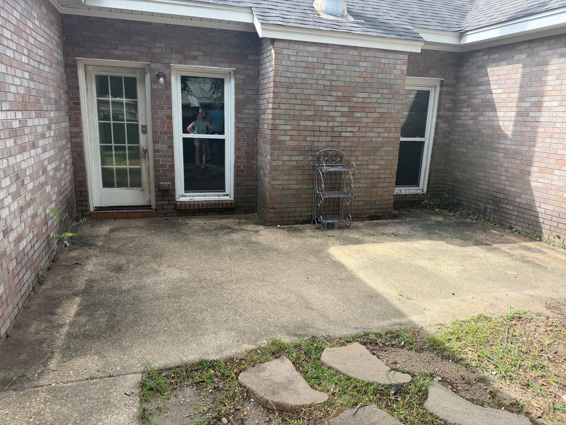 Back brick patio before pressure washing with dirt buildup on the concrete