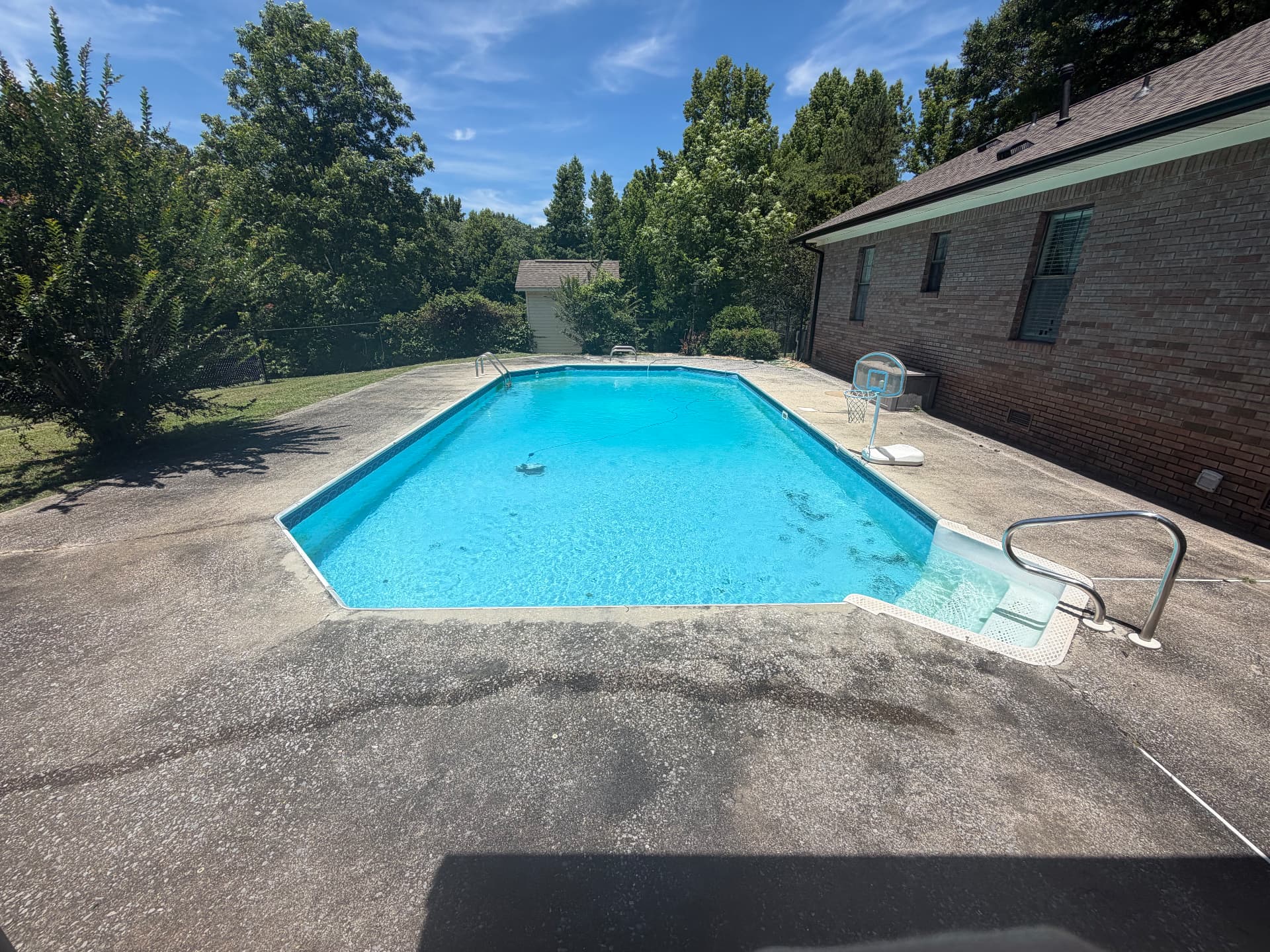 Concrete pool deck before pressure washing, dark and stained